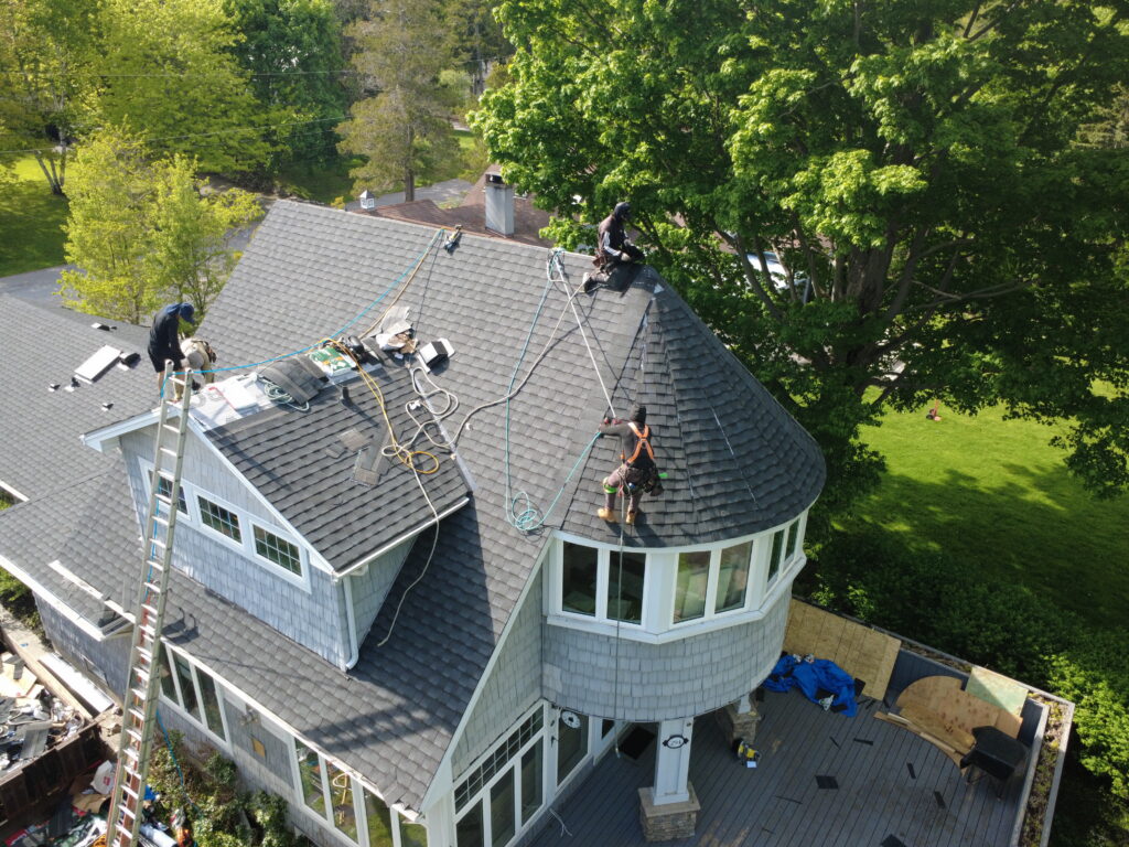 Roofers installing new shingles on a Fort Erie home with a turret