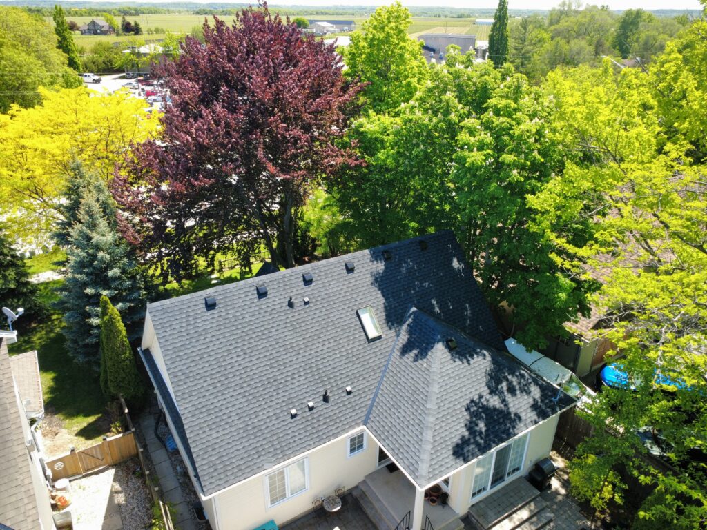 Two-storey home in Niagara-on-the-Lake with a new dark grey shingle roof among mature trees