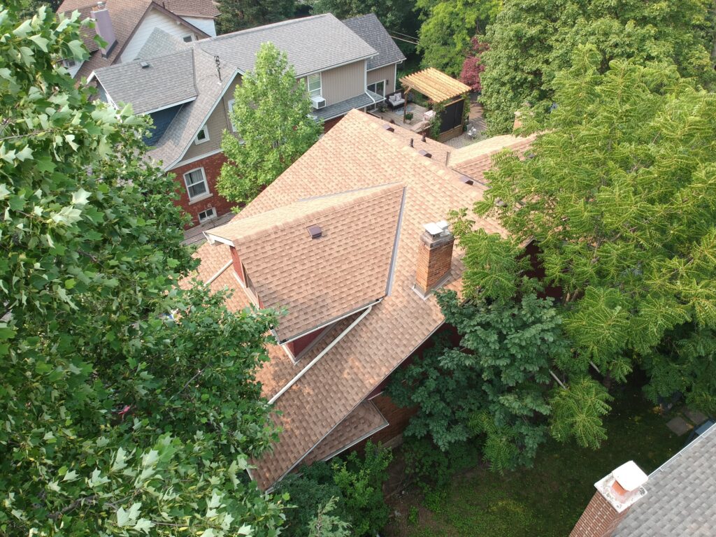 St. Catharines home with a new tan shingle roof among mature trees