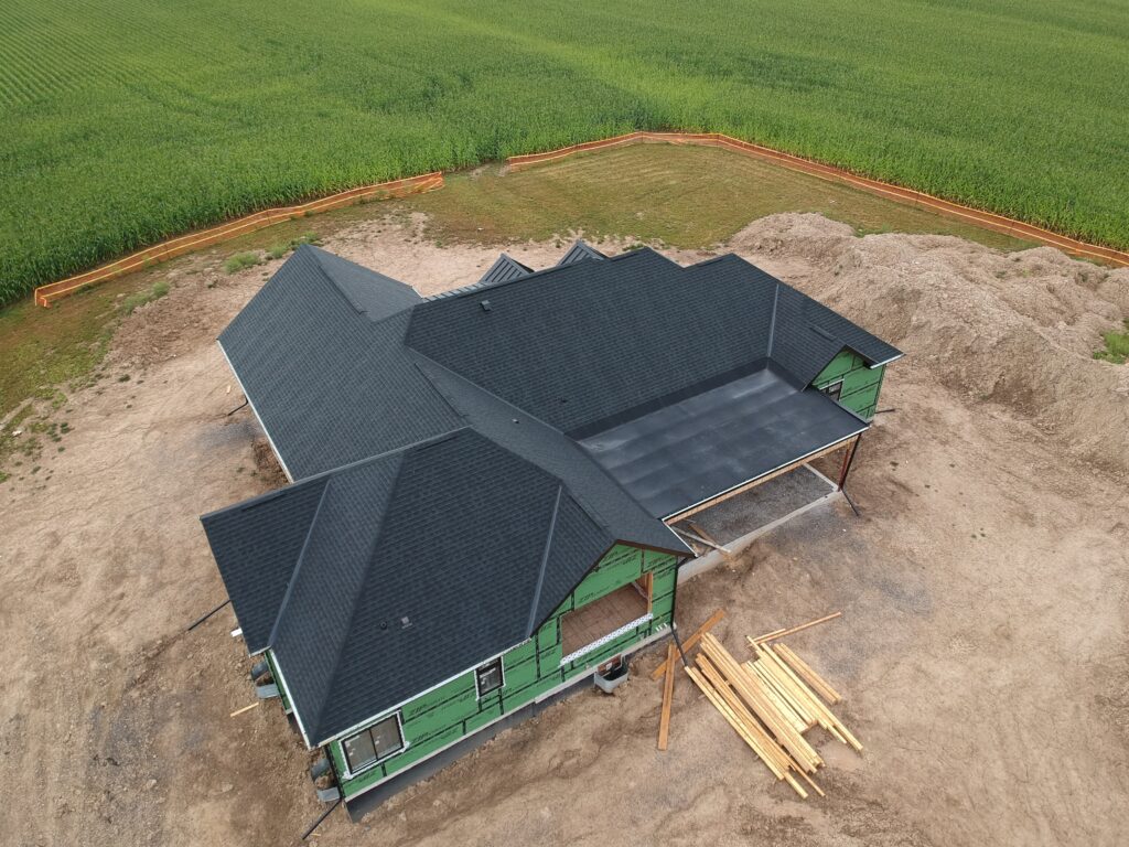 New-build rural home with a dark shingle roof under construction