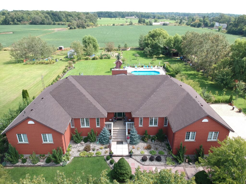 Rural brick home with a new shingle roof surrounded by fields