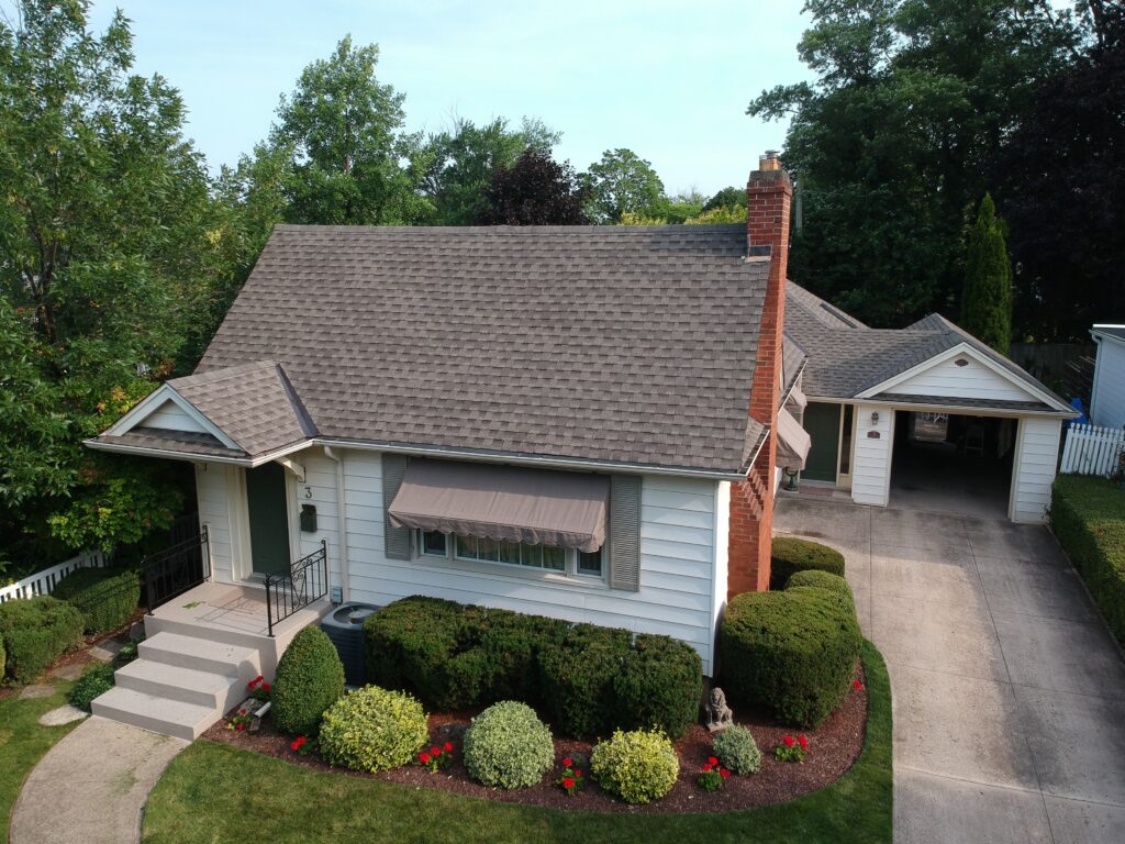 Storey-and-a-half home in St. Catharines with a new brown shingle roof and front awning