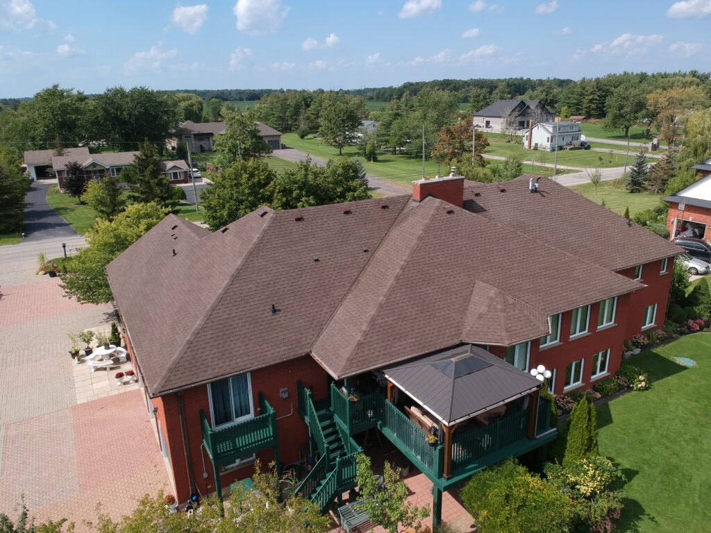 Brick bungalow with a new brown shingle roof and covered deck, aerial view